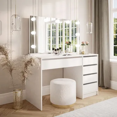 A white vanity table with a mirror and LED lights, a stool, and decorative plants in a bright room.