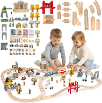 Two young children playing with a wooden train set on the floor.