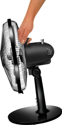 A hand is shown adjusting a black and silver desk fan.
