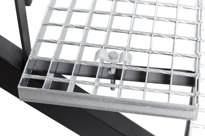 A close-up view of a metal grate with a bolt and wingnut securing it to a black metal frame.
