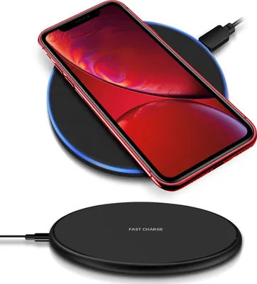A red smartphone is placed on a black wireless charging pad, which is connected to a power source.