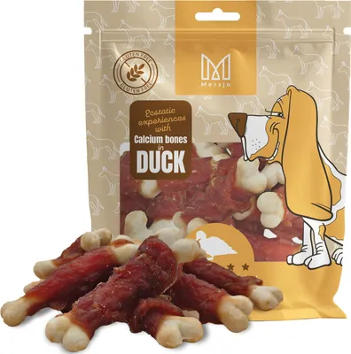 A bag of dog treats with some treats spilled in front.