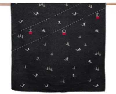 A dark blanket with a repeating pattern of skiers and ski lifts.