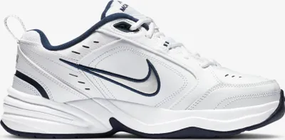 A white Nike Air Monarch IV sneaker with navy accents, shown from the side against a white background.
