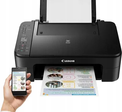 A black Canon Pixma printer is shown with a sheet of paper being printed. A hand holds a smartphone in front of the printer.