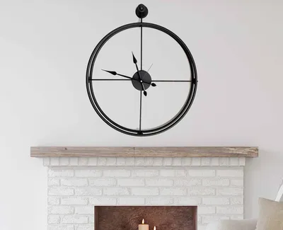 A black metal wall clock hangs above a white brick fireplace.