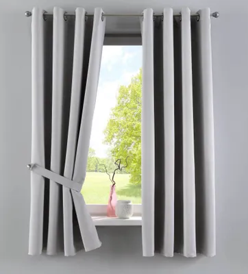 A window with gray curtains, one of which is tied back with a fabric strap. A pink vase and a white decorative object are on the windowsill.