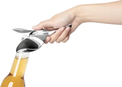 A hand is using a bottle opener to open a bottle of beer.