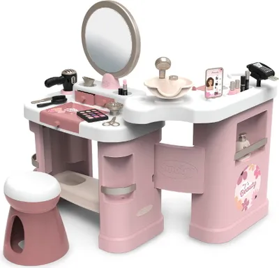 A toy beauty center with various accessories, including a mirror, hairdryer, makeup, and a stool.
