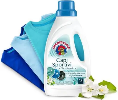 A bottle of Chante Clair laundry detergent for sportswear and synthetic fibers, with a stack of folded t-shirts in various shades of blue and teal.
