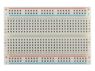 A top-down view of a white breadboard with blue and red power rails.