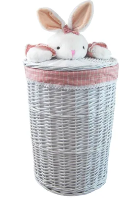 A white wicker laundry basket with a pink gingham trim and a plush bunny toy peeking out from the lid.