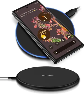 A smartphone is placed on a wireless charging pad, which is connected to a power source.