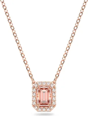 A close-up studio shot of a rose gold necklace with a rectangular pink gemstone pendant surrounded by small white crystals.