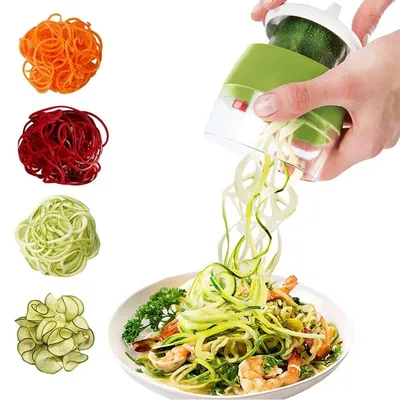 A hand is using a spiralizer to create vegetable noodles, which are falling into a bowl of food.