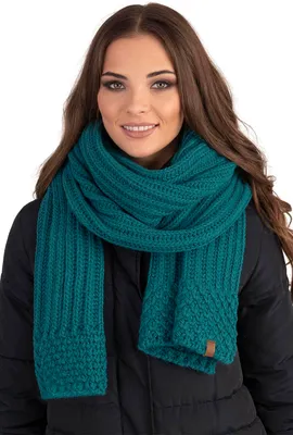 A woman wearing a dark jacket and a teal scarf.