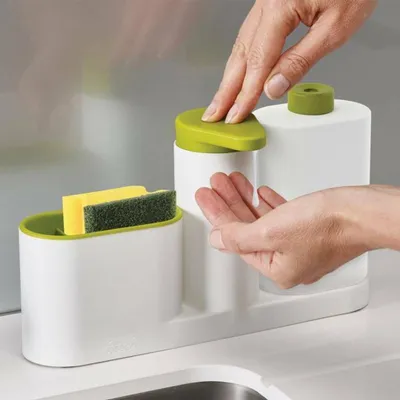 A person's hands are shown using a dish soap dispenser and sponge holder set next to a sink.