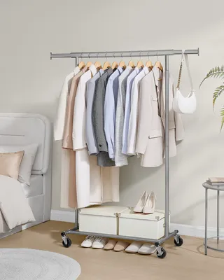 A clothing rack with clothes and shoes in a bedroom setting.