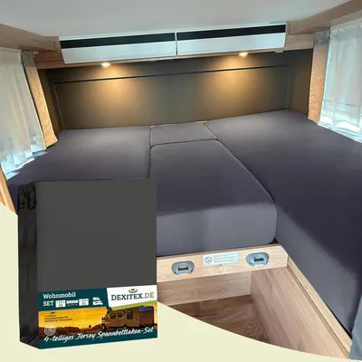 A bed in a camper van with dark gray fitted sheets.