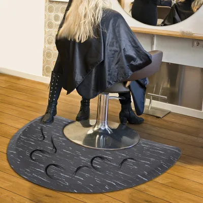 A person sitting in a salon chair on a salon mat.