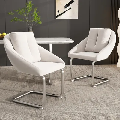Two beige dining chairs with silver metal frames are placed in a dining room setting.