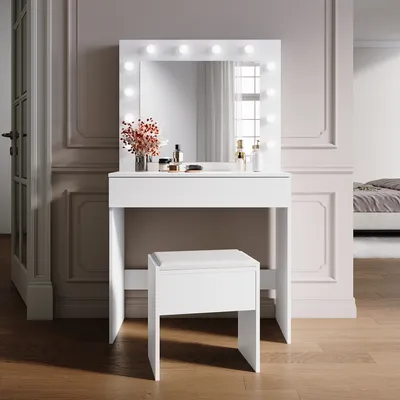 A white vanity table with a lighted mirror and a stool in a room.