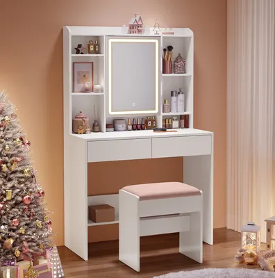 A vanity table with a lighted mirror and stool, set up in a room with a Christmas tree and gifts.