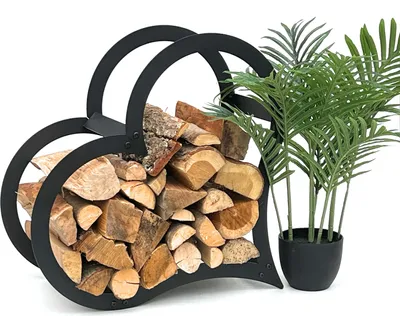 A black metal heart-shaped firewood rack filled with logs, placed next to a potted plant.