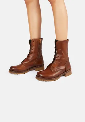 A pair of brown leather lace-up boots worn by a person, shown from the mid-calf down.