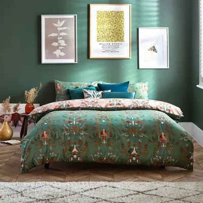 A bedroom scene with a bed dressed in a patterned duvet cover, pillows, and artwork on the wall.
