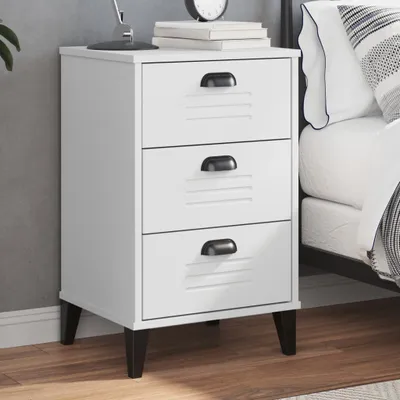 A white bedside table with three drawers next to a bed.