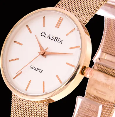 Close-up of a rose gold watch with a white face and mesh band.