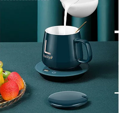 A dark teal mug with the word 'Lucky' on it is being filled with milk, sitting on a matching coaster. A small dish of strawberries is in the foreground.