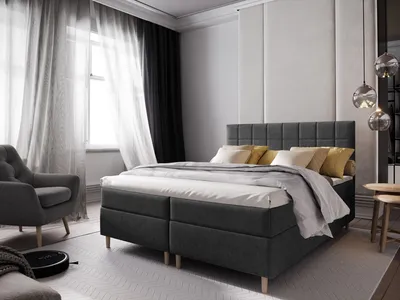 A bedroom scene featuring a large boxspring bed with pillows and a duvet, a chair, and curtains.