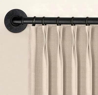 A close-up view of a black curtain rod with beige curtains hanging from it.