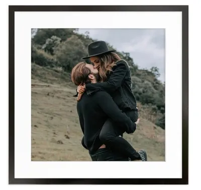 A couple embracing outdoors with a hilly, green background.