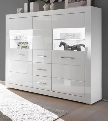 A white highboard with glass shelves and drawers, illuminated from within, is shown against a gray wall.