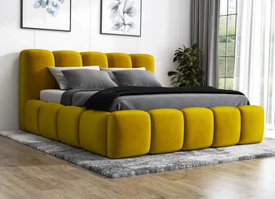 A modern yellow upholstered bed with a mattress and pillows, set on a gray rug in a room with artwork on the wall.