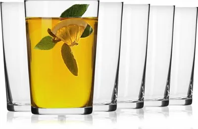 A set of clear glasses, one filled with a yellow beverage and garnished with lemon and mint leaves, arranged on a white background.