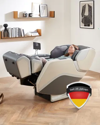 A woman is relaxing in a massage chair in a well-lit room with shelves and artwork on the wall.