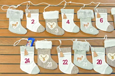 A string of small Christmas stockings hanging on a wooden background.