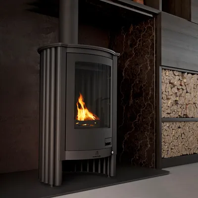 A modern living room with a black wood-burning stove, a marble-patterned wall, and a stack of firewood.