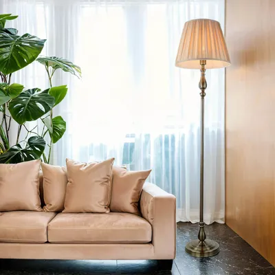 A floor lamp stands next to a sofa in a living room.