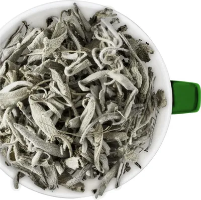 Dried sage leaves in a white bowl with a green handle.