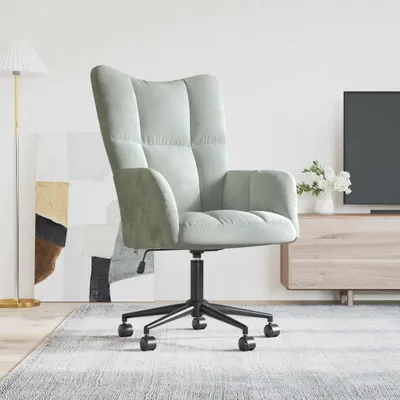 A light green velvet office chair with a black base and wheels is shown in a room with a rug, a floor lamp, and a TV stand.