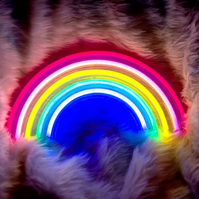 A neon rainbow light is displayed on a fluffy, textured surface.