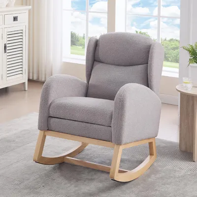 A gray rocking chair with wooden legs is placed on a rug in a room with a window in the background.