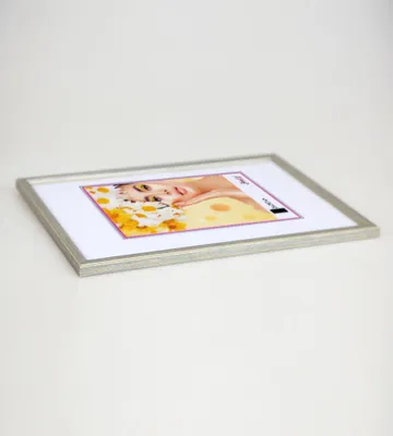 A silver picture frame with a picture of a woman and flowers inside, placed on a white surface.