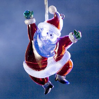 A close-up of a decorative Santa Claus ornament, lit from within, against a blue background.