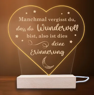 A heart-shaped LED lamp with a quote, resting on a wooden base.